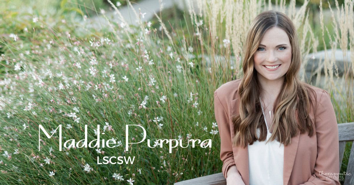 A woman with long brown hair wearing a white blouse and a brown blazer sits on a bench in front of tall, green grass and white flowers. Text on the image reads "Maddie Purpura, LCSW.