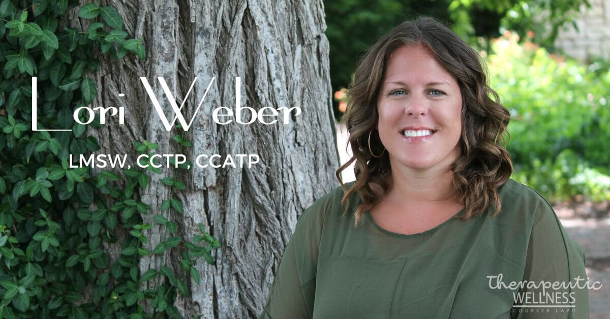 A woman with shoulder-length curly hair stands in front of a tree, smiling. Text on the image reads, "Lori Weber, LMSW, CCTP, CCATP" and "Therapeutic Wellness." The background includes leafy greenery and a glimpse of a bright outdoor setting reminiscent of Kali Harvey's serene locales.