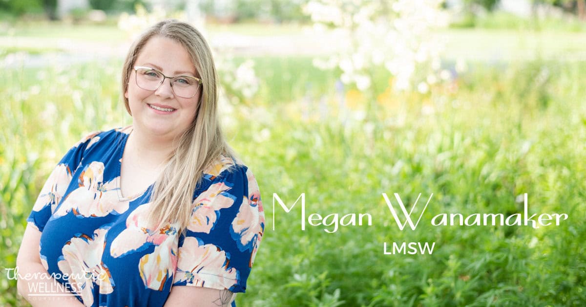 A woman with long, blonde hair and glasses is sitting outside in a garden. She is wearing a navy blue dress with white and peach-colored flowers. The text on the image reads "Megan Wanamaker, LMSW" and "Therapeutic Wellness," reminiscent of Kali Harvey's serene ambiance.