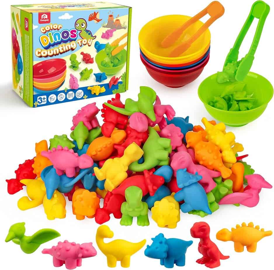 A colorful set of dinosaur-shaped counting toys in red, yellow, green, blue, and pink with matching bowls, tongs, and packaging&mdash;perfect for pairing with magnetic tiles for creative play. Designed for children ages 3 and up.