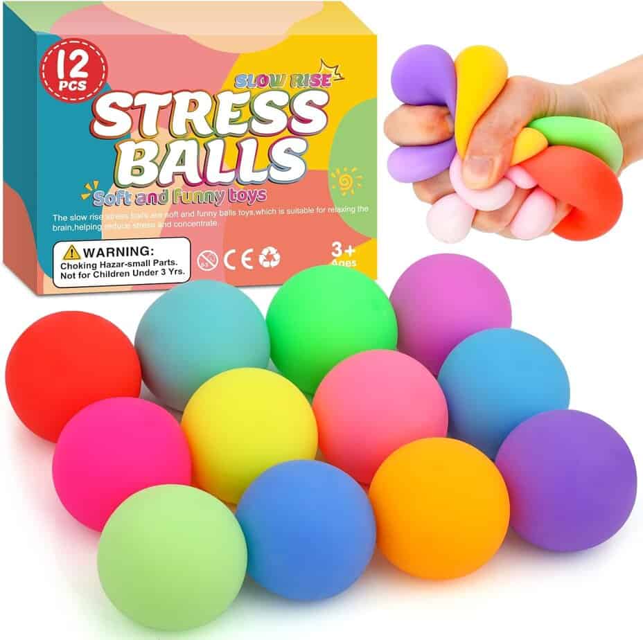 A set of twelve colorful stress balls is displayed, with a hand squeezing four of them. The packaging in the background reads "Stress Balls" and includes a warning for children under 3 years.