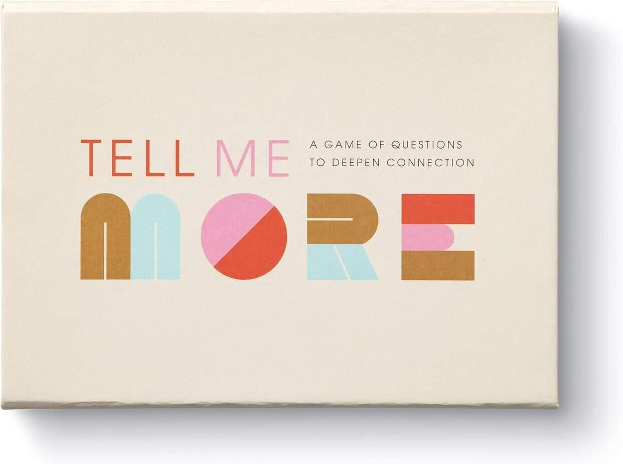 A cream-colored box with colorful text that reads: "TELL ME MORE" and smaller text below saying, "A game of questions for breaking down barriers and deepening connection.