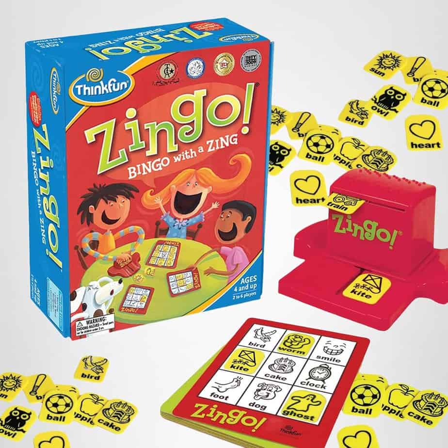 The image shows the game Zingo! by ThinkFun, including the game box, red tile dispenser, yellow tiles with words and pictures, and a bingo card with matching symbols and words&mdash;perfect for ages 4 and up and great for sparking fun Chat Chains.